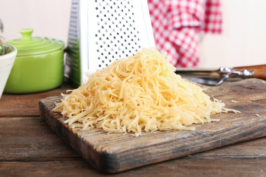 Grated cheese on wooden cutting board in kitchen