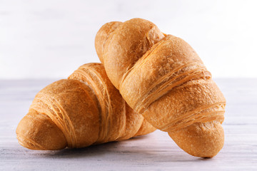 Delicious croissants on table on light background