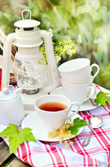 A cup of tea with currents on a terrace, vintage objects, outdoors, selective focus
