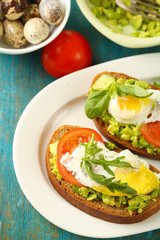 Tasty sandwiches with egg, avocado and vegetables on plate, on wooden background