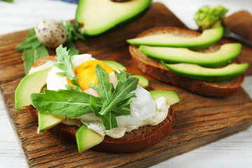 Tasty sandwiches with egg, avocado and vegetables on wooden background