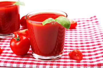 Glasses of fresh tomato juice on checkered napkin, closeup