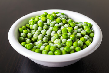 A white bowl with frozen green peas in the kitchen