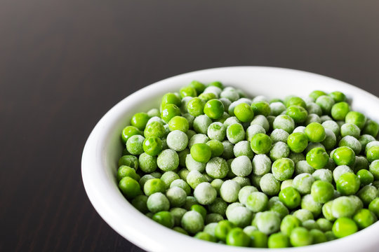 A white bowl with frozen green peas in the kitchen