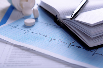 Cardiogram with pills on table, closeup