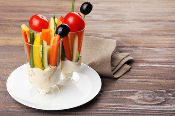 Snack of vegetables in glassware on wooden background