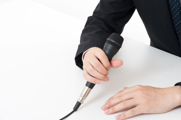 記者会見でマイクを使って謝罪している役員