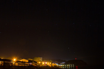 The stars over the night sea city on the beach.