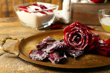Making candied rose flower petals with egg whites and sugar, on wooden background