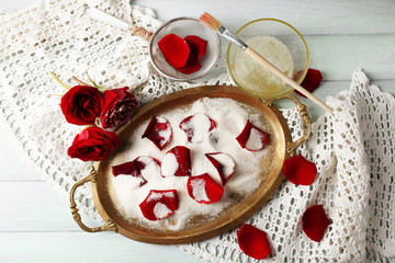 Making candied rose flower petals with egg whites and sugar, on wooden background