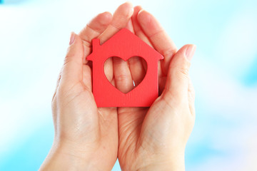 Female hands holding model of house on bright background