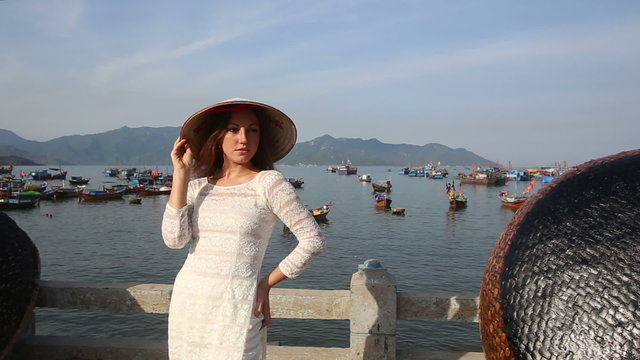 girl in vietnamese poses among boats on embankment