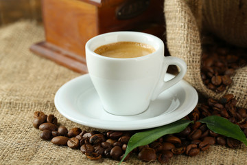 Cup of coffee with beans on table close up
