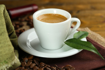 Cup of coffee with beans on table close up