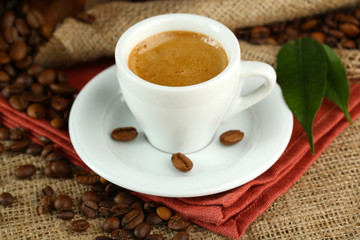 Cup of coffee with beans on table close up