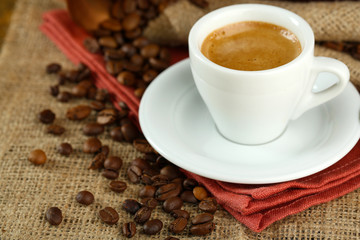 Cup of coffee with beans on table close up