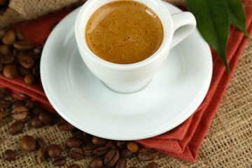 Cup of coffee with beans on table close up