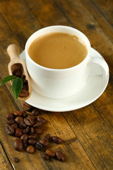 Cup of coffee with beans on table close up