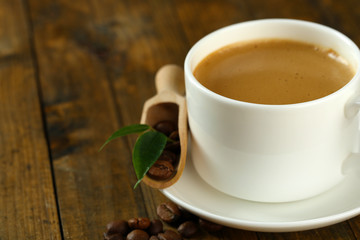 Cup of coffee with beans on table close up