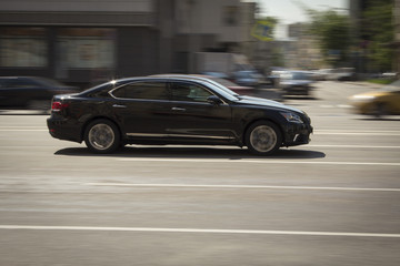 Obraz na płótnie Canvas Black lexus fast driving on a city street.