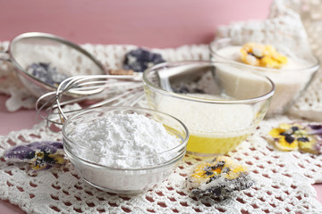 Making candied violet flowers with egg whites and sugar, on color wooden background