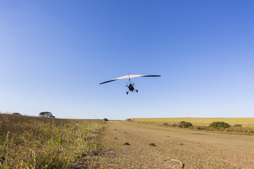 Flying microlight aircraft planes take-off on rural grass airstrip.
