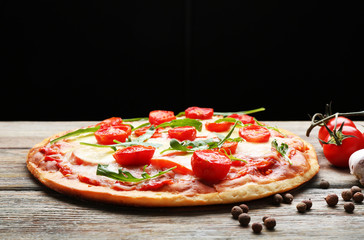 Delicious pizza with cheese and cherry tomatoes on wooden table on dark background