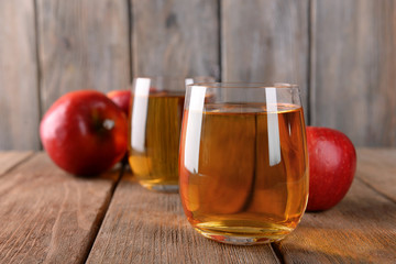 Glasses of apple juice on wooden background