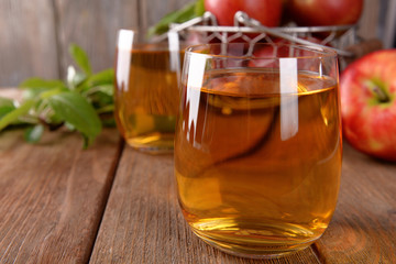 Glasses of apple juice on wooden table, closeup