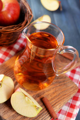 Glass jug of apple juice on wooden table, closeup