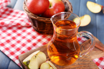 Glass jug of apple juice on wooden table, closeup