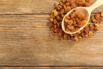 Raisins in spoon on wooden background