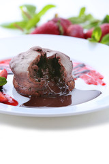 Chocolate fondant with strawberries on white plate, closeup