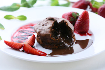 Chocolate fondant with strawberries on white plate, closeup