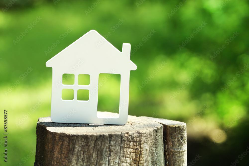 Sticker Small model of house on stump on green blurred background