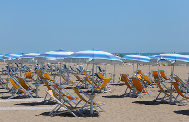 sunbeds with umbrellas in sunny beach in summer - obrazy, fototapety, plakaty