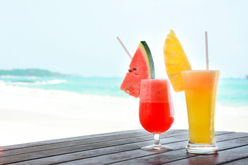 Colorful tropical fruit juice smoothies in the glasses on blur beach background