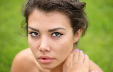 Woman model posing against green natural background.