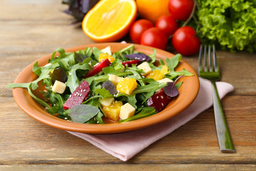 Tasty salad with arugula leaves in plate on wooden table, closeup