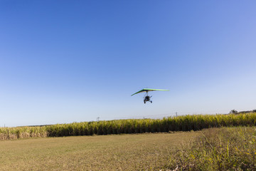Flying microlight aircraft planes take-off on rural grass airstrip.