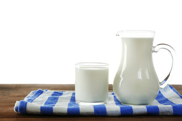 Pitcher and glass of milk on wooden table, on white background