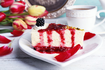 Tasty piece of cheesecake with berry sauce on plate on table close up