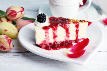 Tasty piece of cheesecake with berry sauce on plate on table close up