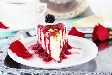 Tasty piece of cheesecake with berry sauce on plate on table close up