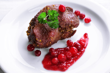 Tasty roasted meat with cranberry sauce on plate, close-up