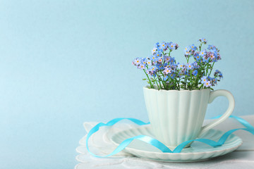 Forget-me-nots flowers in cup, on blue background