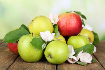 Naklejka na ściany i meble Fresh apples with apple blossom on wooden table, on nature background