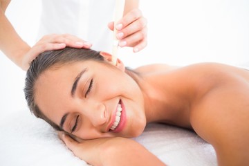 Beautiful woman receiving ear candle treatment at spa center