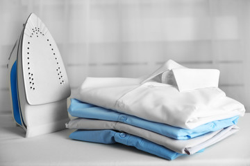Pile of clothes and electric iron on fabric background