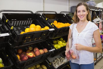 Smiling pretty blonde woman buying apples